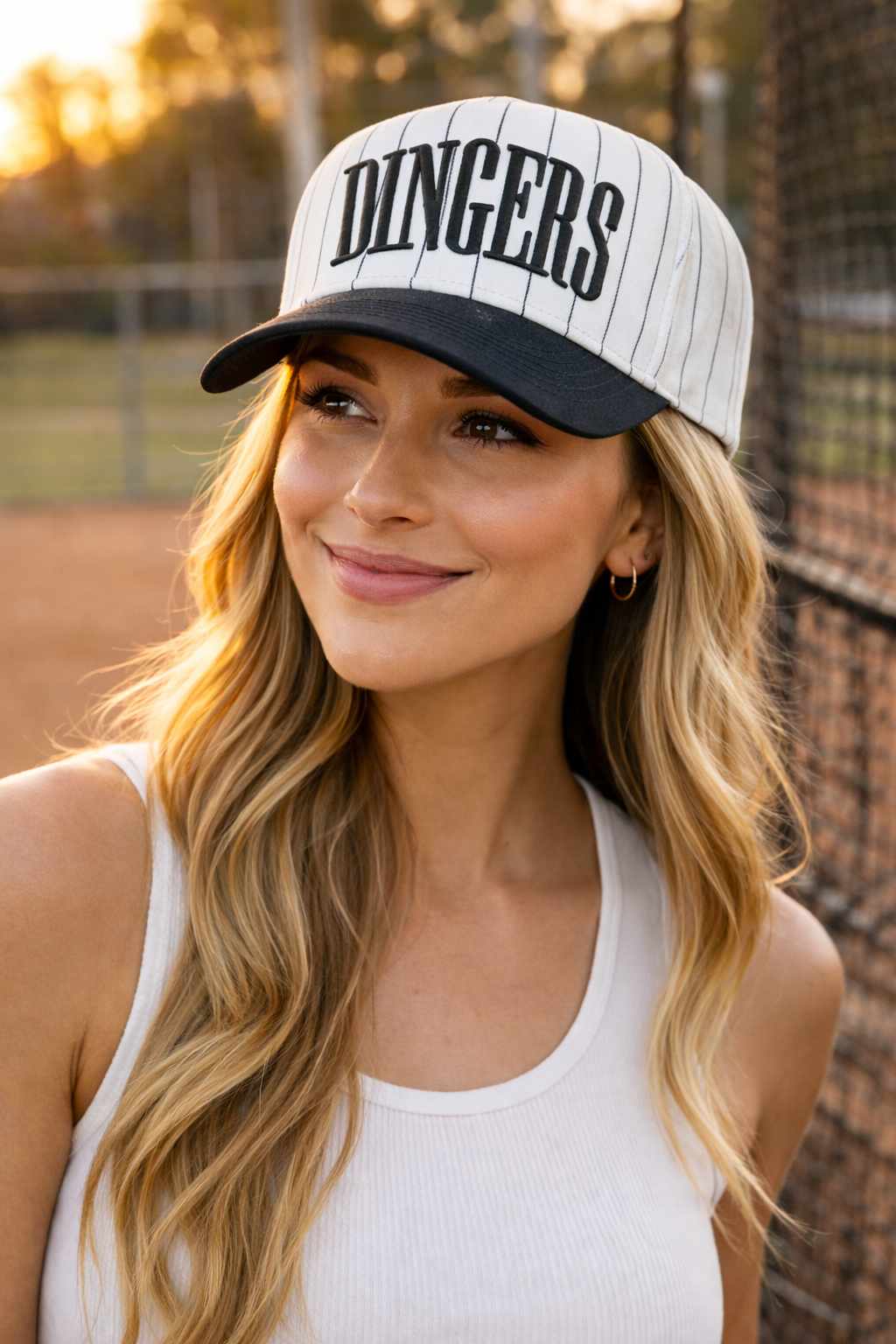 Female model wearing DINGERS pinstripe baseball snapback hat at a baseball field
