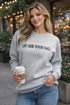 Woman wearing a gray sweatshirt with &