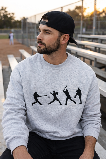 Male model wearing gray baseball crewneck sweatshirt at a baseball field